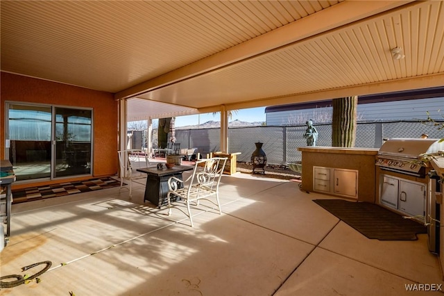 view of patio / terrace with an outdoor kitchen, outdoor dining area, area for grilling, and fence