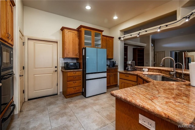 kitchen featuring light tile patterned floors, brown cabinetry, a sink, and a warming drawer