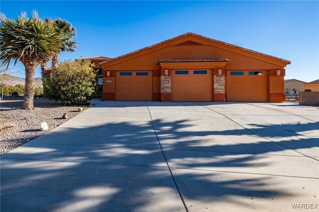 view of front of home with concrete driveway, stone siding, and stucco siding