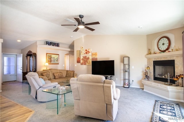 living area with arched walkways, a tile fireplace, carpet floors, baseboards, and vaulted ceiling