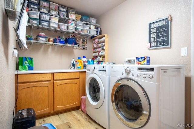 laundry area featuring light wood-type flooring, washing machine and dryer, and cabinet space