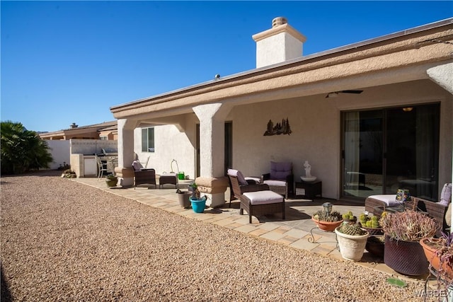 rear view of house featuring stucco siding, a chimney, fence, and a patio