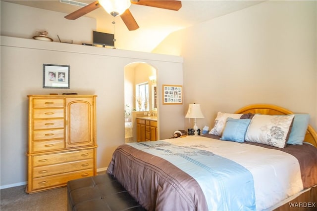 bedroom featuring arched walkways, a ceiling fan, ensuite bathroom, vaulted ceiling, and carpet floors