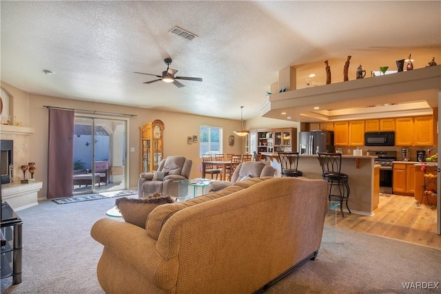 living room with light carpet, visible vents, a textured ceiling, and a premium fireplace