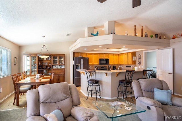 living room with light wood finished floors, visible vents, baseboards, ceiling fan, and a textured ceiling