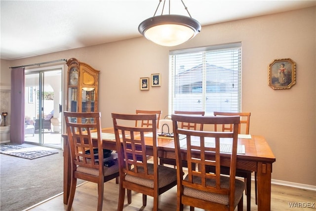 dining space featuring light wood-style floors and baseboards