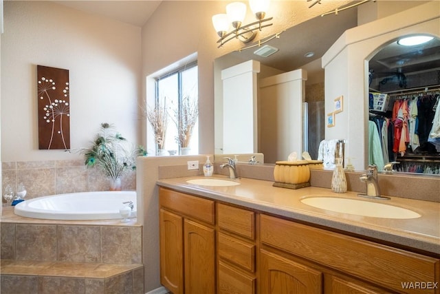 bathroom with a garden tub, double vanity, and a sink