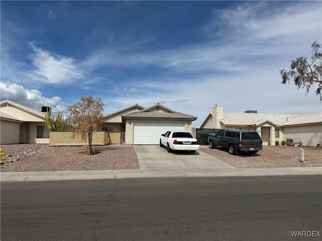 view of front facade with a garage, fence, a tile roof, concrete driveway, and stucco siding