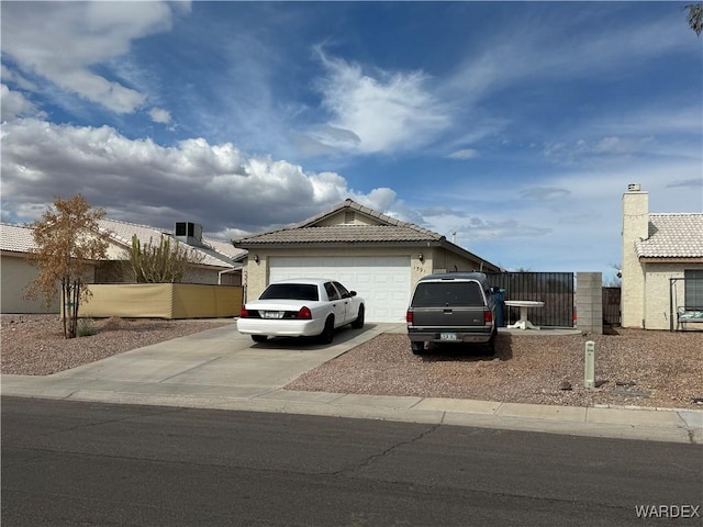 view of front of home featuring an attached garage, a tile roof, fence, concrete driveway, and stucco siding