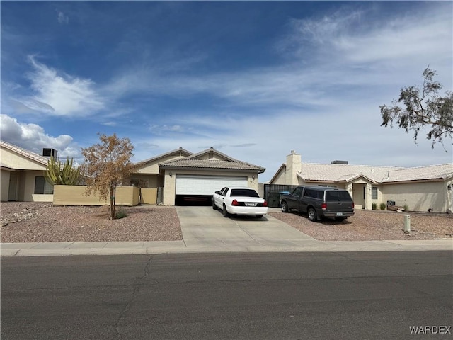 view of front of home with a garage, fence, concrete driveway, and a tiled roof