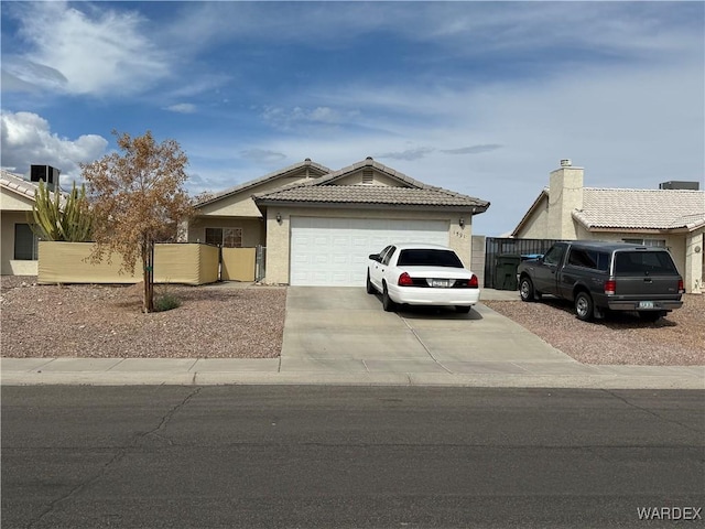 ranch-style house featuring driveway, a garage, a tile roof, fence, and stucco siding