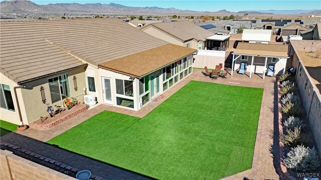 back of property with a fenced backyard, a mountain view, a yard, a residential view, and a patio area