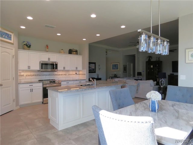 kitchen featuring white cabinets, an island with sink, stainless steel appliances, pendant lighting, and a sink