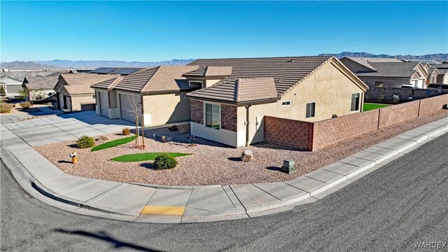 ranch-style house featuring concrete driveway, fence, a residential view, and stucco siding