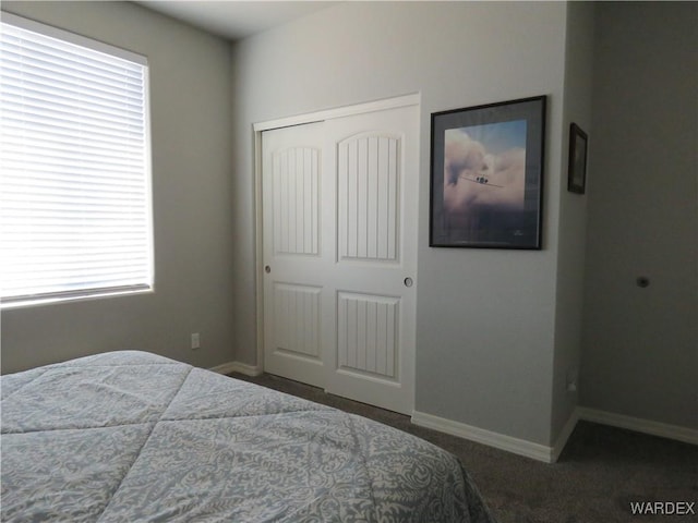 bedroom featuring dark colored carpet, a closet, and baseboards