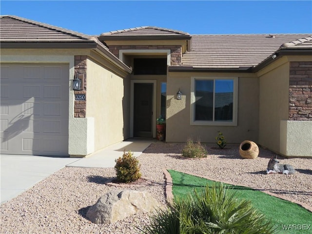 view of exterior entry with a garage, stone siding, a tile roof, and stucco siding