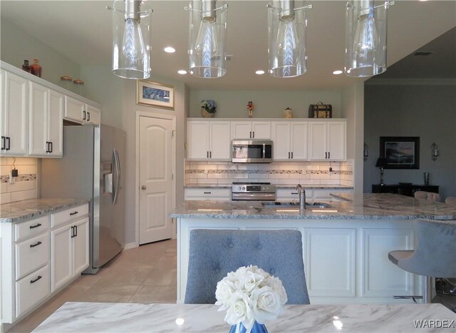 kitchen featuring stainless steel appliances, pendant lighting, white cabinetry, and a sink