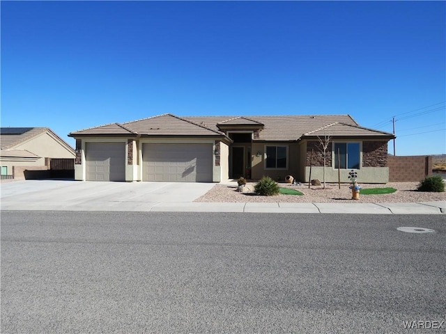 view of front facade featuring a garage, a tiled roof, concrete driveway, and stucco siding