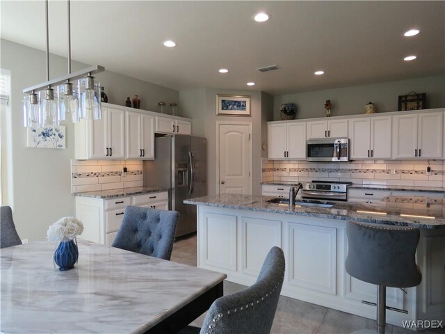 kitchen featuring appliances with stainless steel finishes, white cabinets, and light stone counters