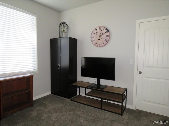 living area with dark colored carpet and baseboards