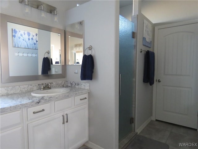 bathroom with a stall shower, vanity, and baseboards