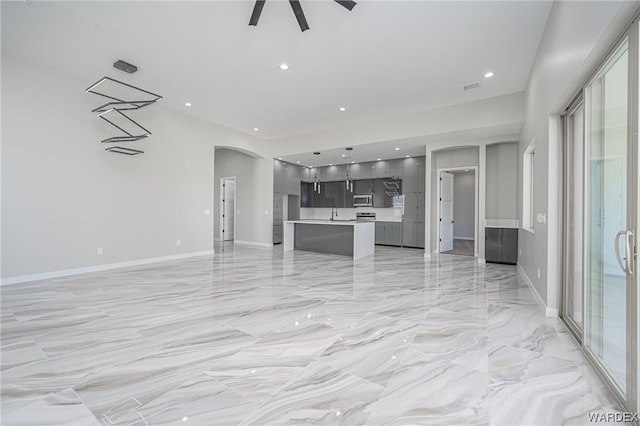 unfurnished living room featuring arched walkways, marble finish floor, recessed lighting, ceiling fan, and baseboards