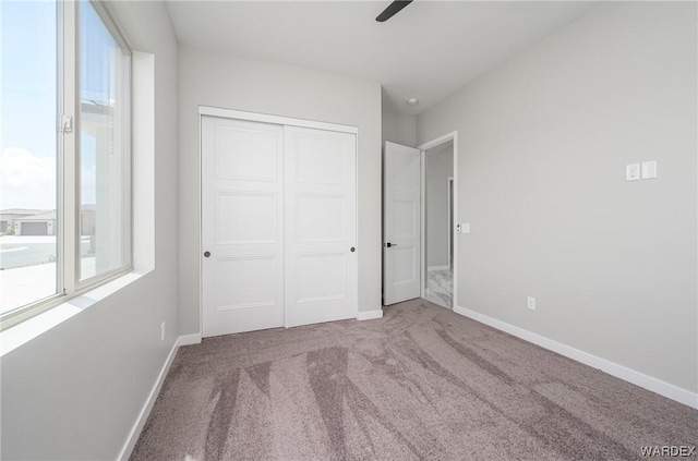 unfurnished bedroom with carpet floors, a ceiling fan, baseboards, and a closet