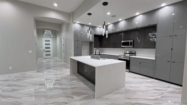 kitchen with stainless steel appliances, a sink, hanging light fixtures, light countertops, and modern cabinets