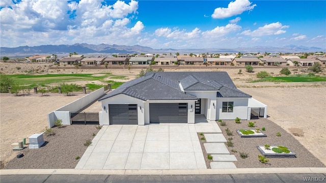 view of front of home with a garage, a residential view, a mountain view, and fence