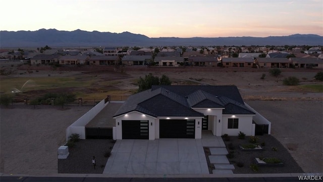 view of front of home featuring a residential view, concrete driveway, a mountain view, and an attached garage