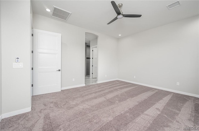 empty room with arched walkways, visible vents, ceiling fan, and light carpet