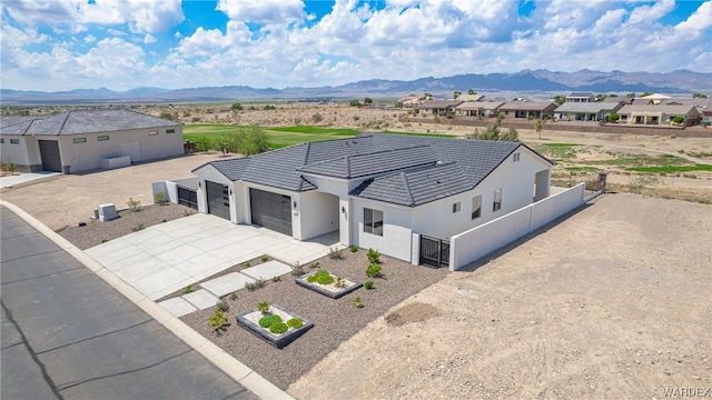 ranch-style home with driveway, a garage, a residential view, and a mountain view