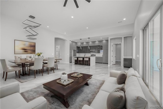 living room with a wealth of natural light, arched walkways, marble finish floor, and recessed lighting