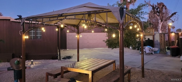 patio terrace at dusk featuring driveway and an attached garage