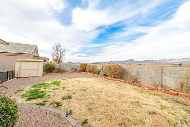 view of yard featuring a storage unit, an outdoor structure, a fenced backyard, and a mountain view