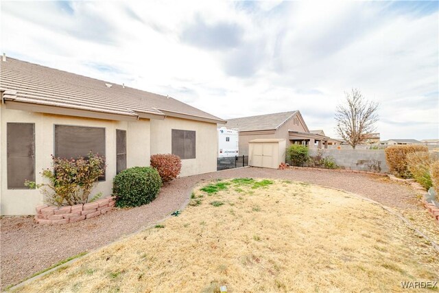 back of house featuring a storage shed, a fenced backyard, an outbuilding, and stucco siding