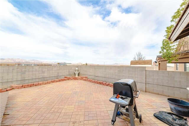 view of patio / terrace featuring a fenced backyard, a grill, and a mountain view