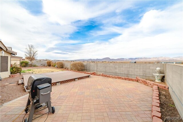 view of patio / terrace featuring a fenced backyard, a mountain view, and grilling area