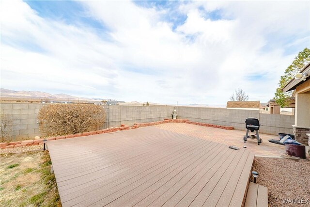 wooden terrace with a patio area, a fenced backyard, and a mountain view