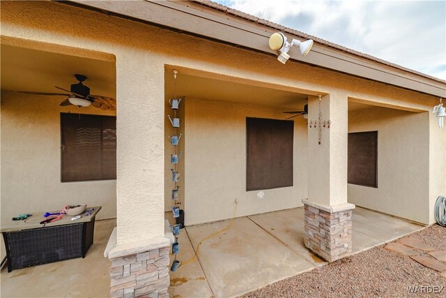 view of exterior entry with a tiled roof, a patio area, a ceiling fan, and stucco siding