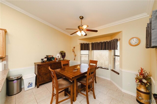 dining room featuring ceiling fan, baseboards, crown molding, and light tile patterned flooring