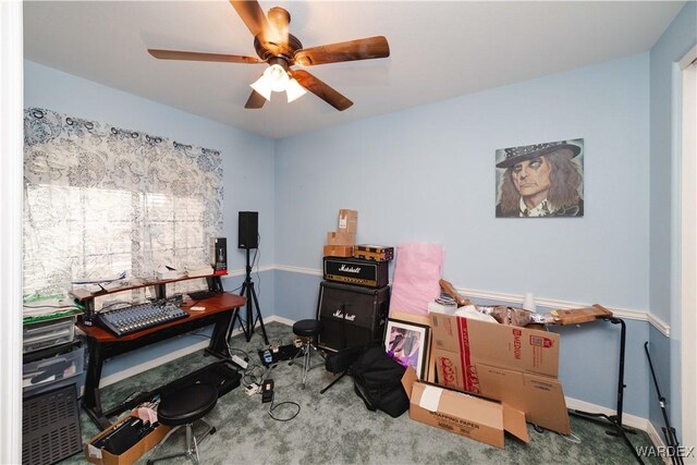 carpeted office space featuring ceiling fan and baseboards