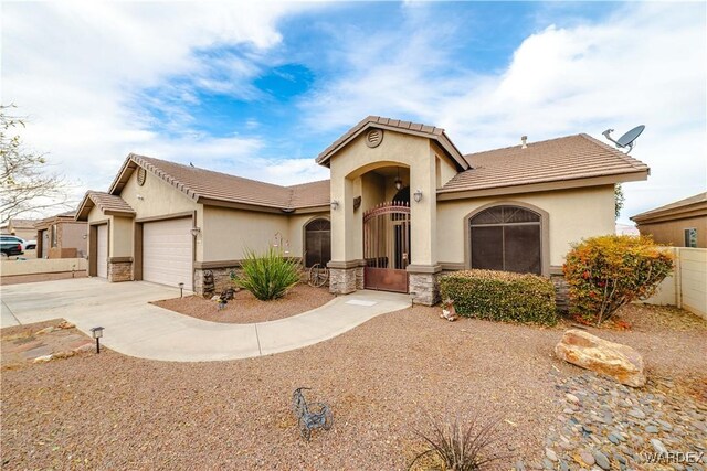 mediterranean / spanish-style home with concrete driveway, stone siding, an attached garage, fence, and stucco siding