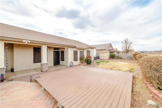 back of house with a patio area, a fenced backyard, a storage unit, and stucco siding