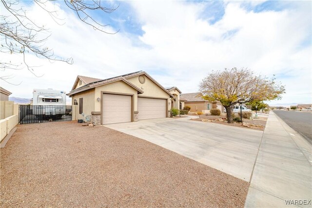 ranch-style home featuring a garage, concrete driveway, fence, and stucco siding