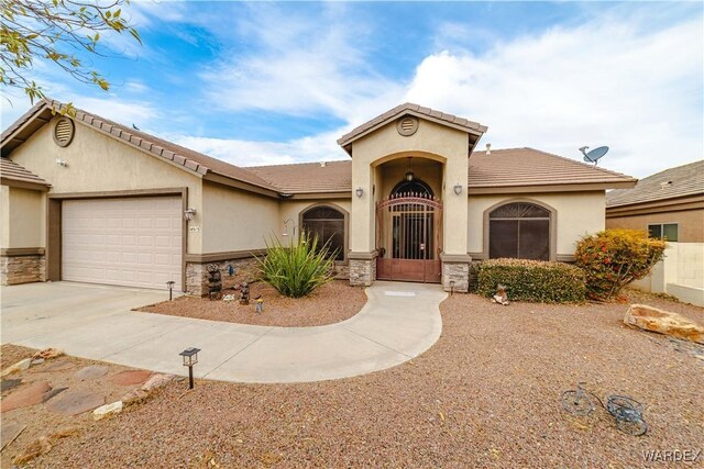 mediterranean / spanish-style house featuring a garage, stone siding, concrete driveway, and stucco siding