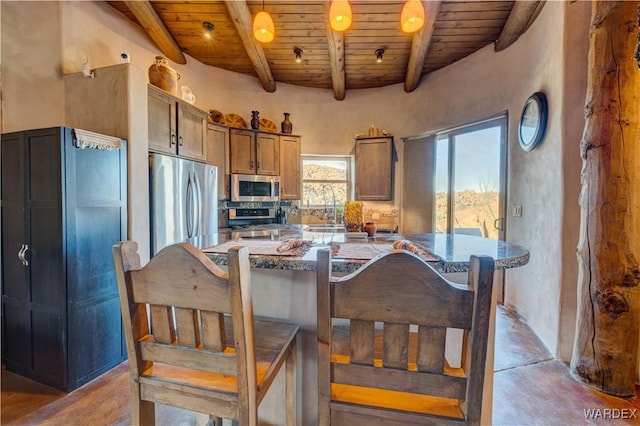 kitchen with beam ceiling, wood ceiling, concrete flooring, and stainless steel appliances