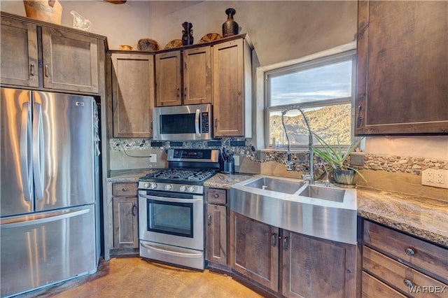 kitchen featuring a sink, stainless steel appliances, light stone counters, and decorative backsplash