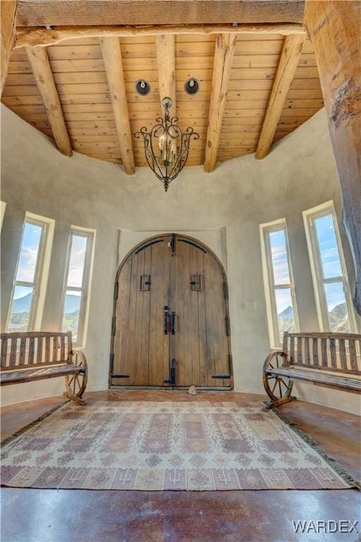 foyer entrance featuring beam ceiling, wood ceiling, concrete floors, and a chandelier