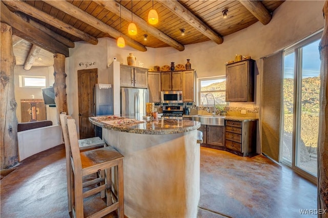 kitchen with a breakfast bar, a sink, finished concrete flooring, stainless steel appliances, and wood ceiling